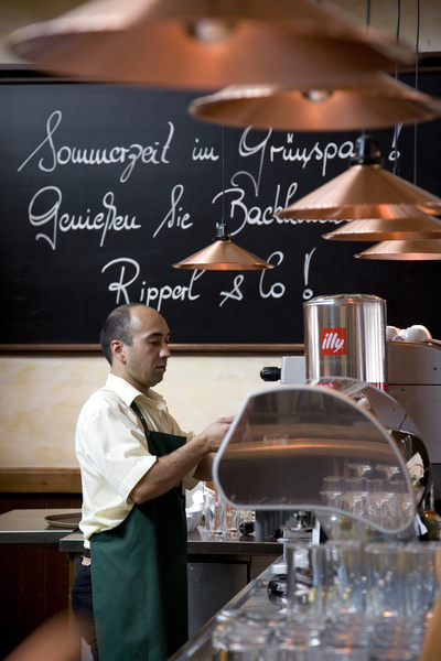 Two hands enclose a small plant with two leaves, symbolizing protection and growth.